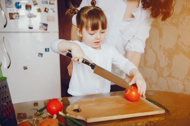 dziecko kroi pomidora dużym nożem
